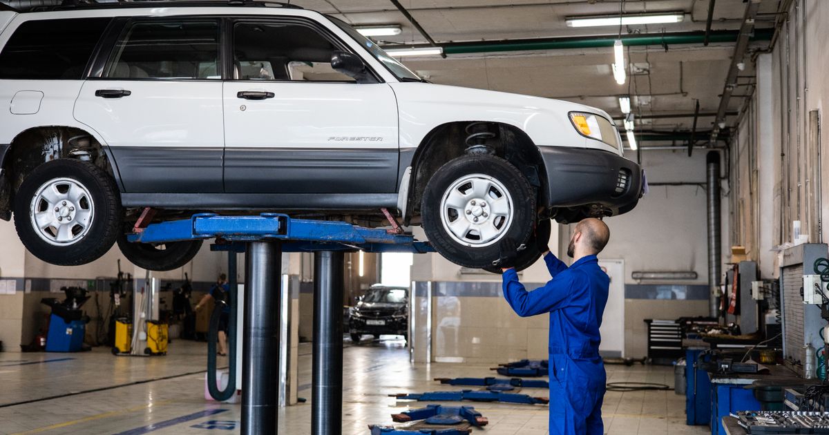 Mecánico profesional inspecciona un carro usado elevado en un taller