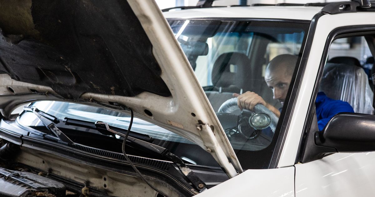 Persona revisa el estado de un carro usado antes de comprarlo