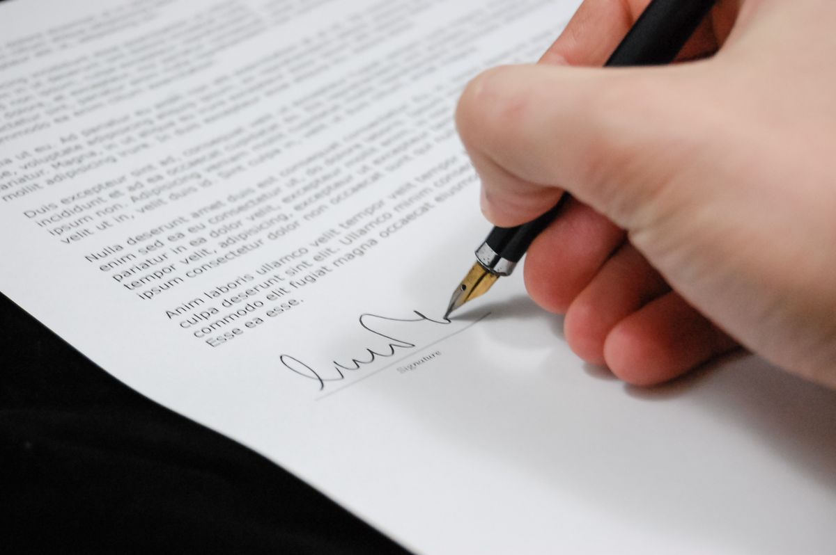 Persona firmando un contrato de compraventa de vehículo con bolígrafo